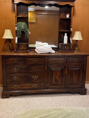 A wooden dresser with multiple drawers and a mirror above it. - Under The Cherry Boon: A Traverse City Dream (Traverse City)