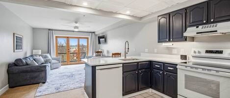 A modern kitchen with dark cabinets, a white countertop, and a built-in oven.