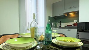 Une table à manger dressée avec des assiettes, des couverts et des verres, une bouteille et un verre posés sur la table.