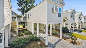 A residential building with a unique elevated structure, a covered outdoor area, and a visible staircase leading to an upper level. - The Pass Picture Book (Pass Christian)
