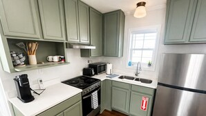 A kitchen with green cabinets, a stainless steel refrigerator, a microwave, a stove, and a sink. - The Pass Picture Book (Pass Christian)