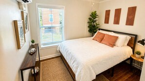 A bedroom with a bed, bedside table, lamp, and a ceiling fan. - The Pass Picture Book (Pass Christian)