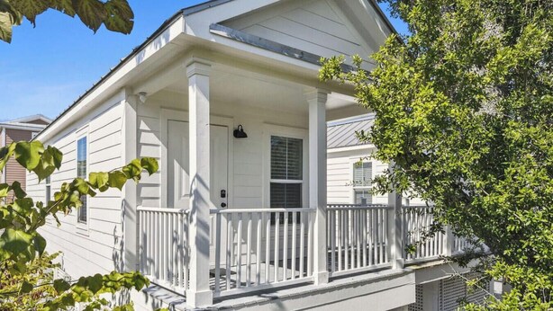 A two-story house with a white exterior, a porch with white railings, and a small window on the second floor. - The Pass Picture Book (Pass Christian)