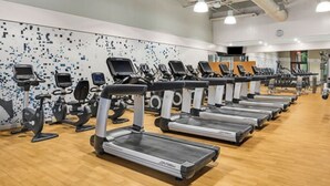Ein Fitnessraum mit mehreren Laufbändern und Ergometer, die in Reihen angeordnet sind.