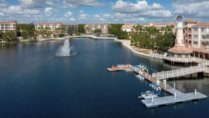 Ein Hotel am Wasser mit einem zentralen Brunnen, Booten, die anlegen, und einer Brücke, die zu den Gebäuden führt.