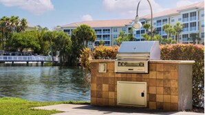 Eine Außenküche mit Grill, einem integrierten Backofen und einem Wasserfall im Hintergrund.