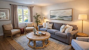 A living room with a sofa, armchairs, a coffee table, a lamp, and a painting on the wall. - A Porter Retreat • 2BR Walk to Downtown OS (Ocean Springs)