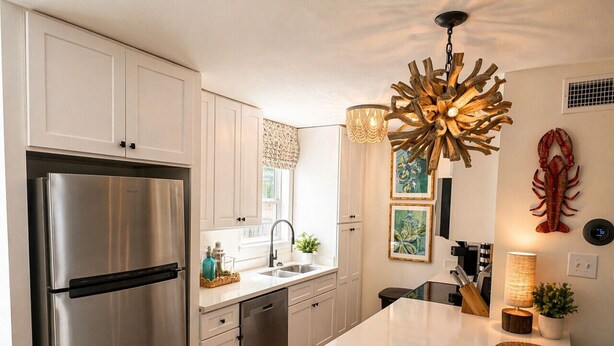 A modern kitchen with white cabinets, stainless steel appliances, a central island, and decorative wall art. - A Porter Retreat • 2BR Walk to Downtown OS (Ocean Springs)