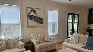 Una sala de estar con un sofá color beige, una mesa de centro y una obra de arte grande enmarcada en la pared.