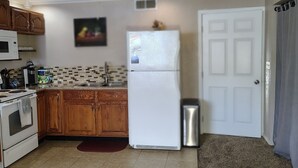 Una cocina con armarios de madera, un refrigerador blanco, un microondas y un ventilador de techo.