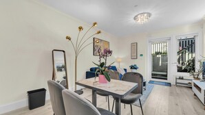 Uma área de refeições com mesa, cadeiras, espelho e um vaso com flores.