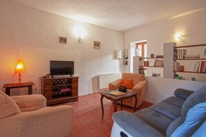 Ein Wohnzimmer mit Fernseher, Sofa, Couchtisch und Bücherregal.