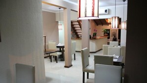 A hotel lobby with a dining area, a reception desk, and a staircase. - Posada Del Jacarandá (Puerto Iguazu)