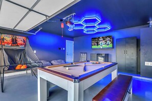 A pool table with a bench, a basketball hoop, a television, and a cabinet. - Backyard Paradise • Hot Tub • Fire Pit • 13 guests (McKinney)