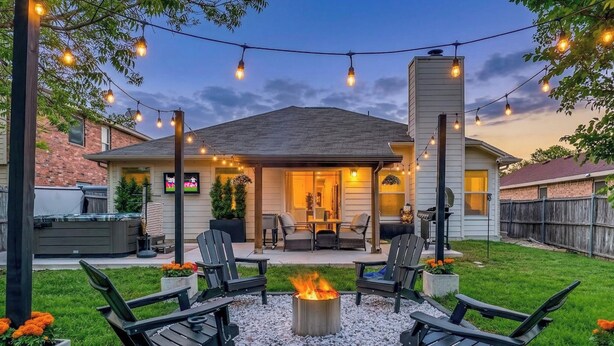 Une terrasse avec des sièges d’extérieur, un foyer et des guirlandes lumineuses.