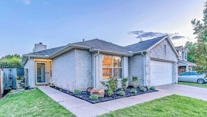 Une maison d’habitation avec un garage, un jardin aménagé à l’avant et une allée.