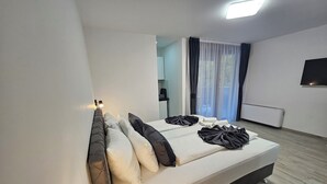 A modern hotel room with a large bed, a flat-screen TV, and a view of the outdoors.