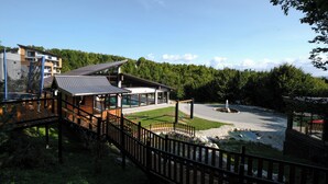 A modern building with a wooden deck, a covered outdoor area, and a parking lot.