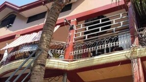 Un edificio de varios pisos con balcones, una escalera y una palmera.