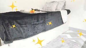 Una cama con una cubierta negra, almohadas, un letrero que dice 'hello' y un libro.