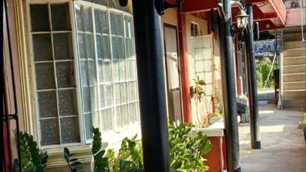 Un edificio con ventanas amplias, un toldo rojo y macetas con plantas.