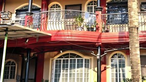 Un edificio con balcón, ventanas de arco y un toldo rojo.