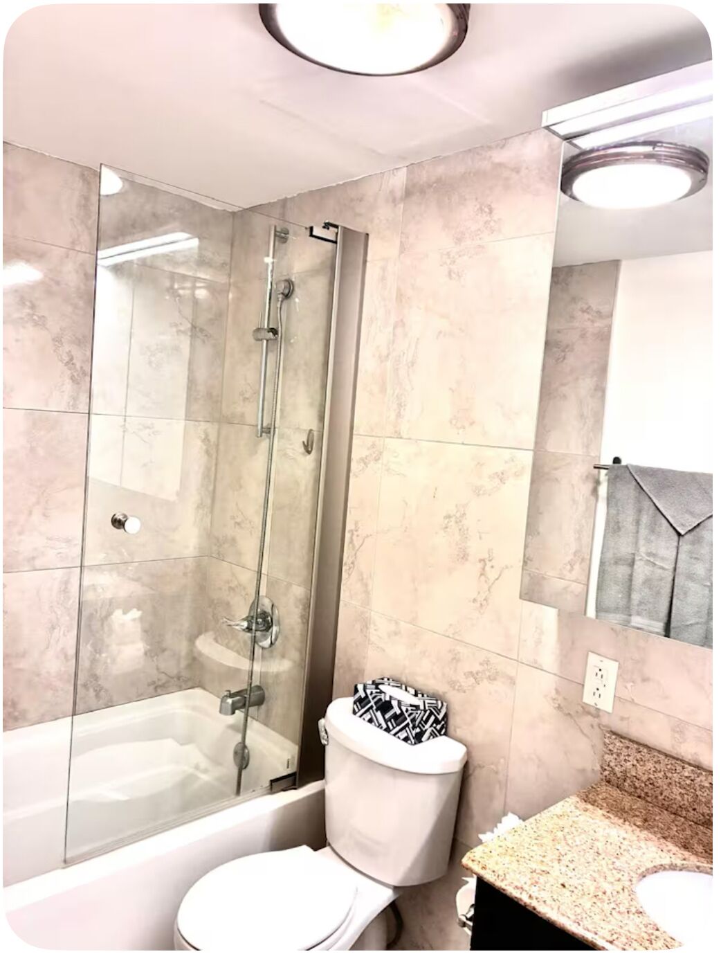A bathroom with a glass-enclosed shower, a toilet, and a sink.