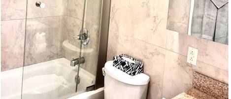 A bathroom with a glass-enclosed shower, a toilet, and a sink.