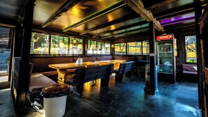 A restaurant with wooden tables and benches, a trash can, and a refrigerator. - 1BDR apartment, shared pool, kitchen, balcony, C21 (Sarajevo)