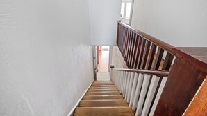 Un escalier avec des marches en bois et des rampes blanches, menant à l’étage supérieur.