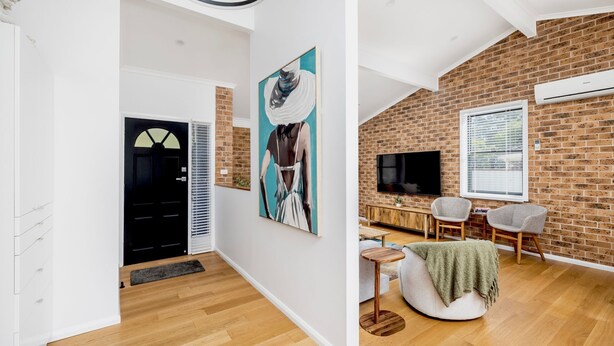 Un salon moderne avec un mur en briques, un téléviseur à écran plat, un canapé et un coin repas.