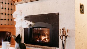 A fireplace with a visible fire, a wall-mounted vent, and a decorative wall panel. - Stunning Chalet at Whispering Springs (Grafton)