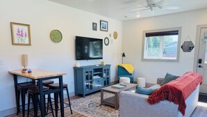 A living room with a sofa, coffee table, TV, and a dining area with chairs and a table. - Modern, Clean and Cozy 2 Bedroom Duplex in Quiet West Fairbanks (Fairbanks)