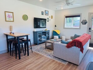 A living room with a sofa, coffee table, TV, and a dining area with chairs and a table. - Modern, Clean and Cozy 2 Bedroom Duplex in Quiet West Fairbanks (Fairbanks)