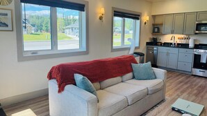 A living room with a sofa, a coffee table, and a kitchen in the background. - Modern, Clean and Cozy 2 Bedroom Duplex in Quiet West Fairbanks (Fairbanks)