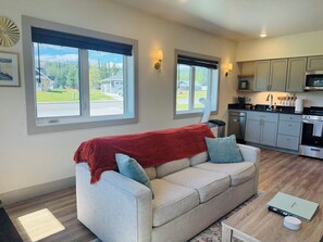 A living room with a sofa, a coffee table, and a kitchen in the background. - Modern, Clean and Cozy 2 Bedroom Duplex in Quiet West Fairbanks (Fairbanks)
