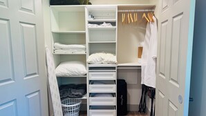 A walk-in closet with open shelves, hanging clothes, and a storage bin. - Modern, Clean and Cozy 2 Bedroom Duplex in Quiet West Fairbanks (Fairbanks)