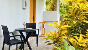 Una habitación con una mesa redonda, dos sillas, una planta pequeña y una puerta.