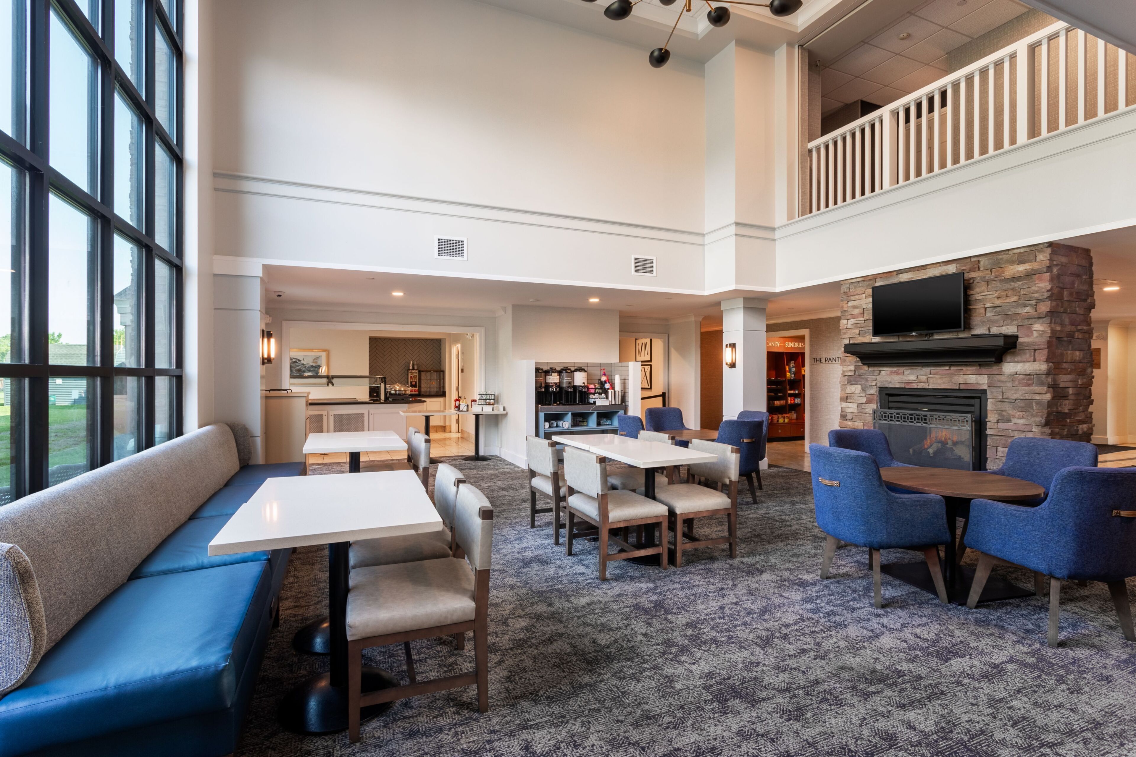 A spacious lobby with a seating area, a fireplace, and a kitchen in the background.