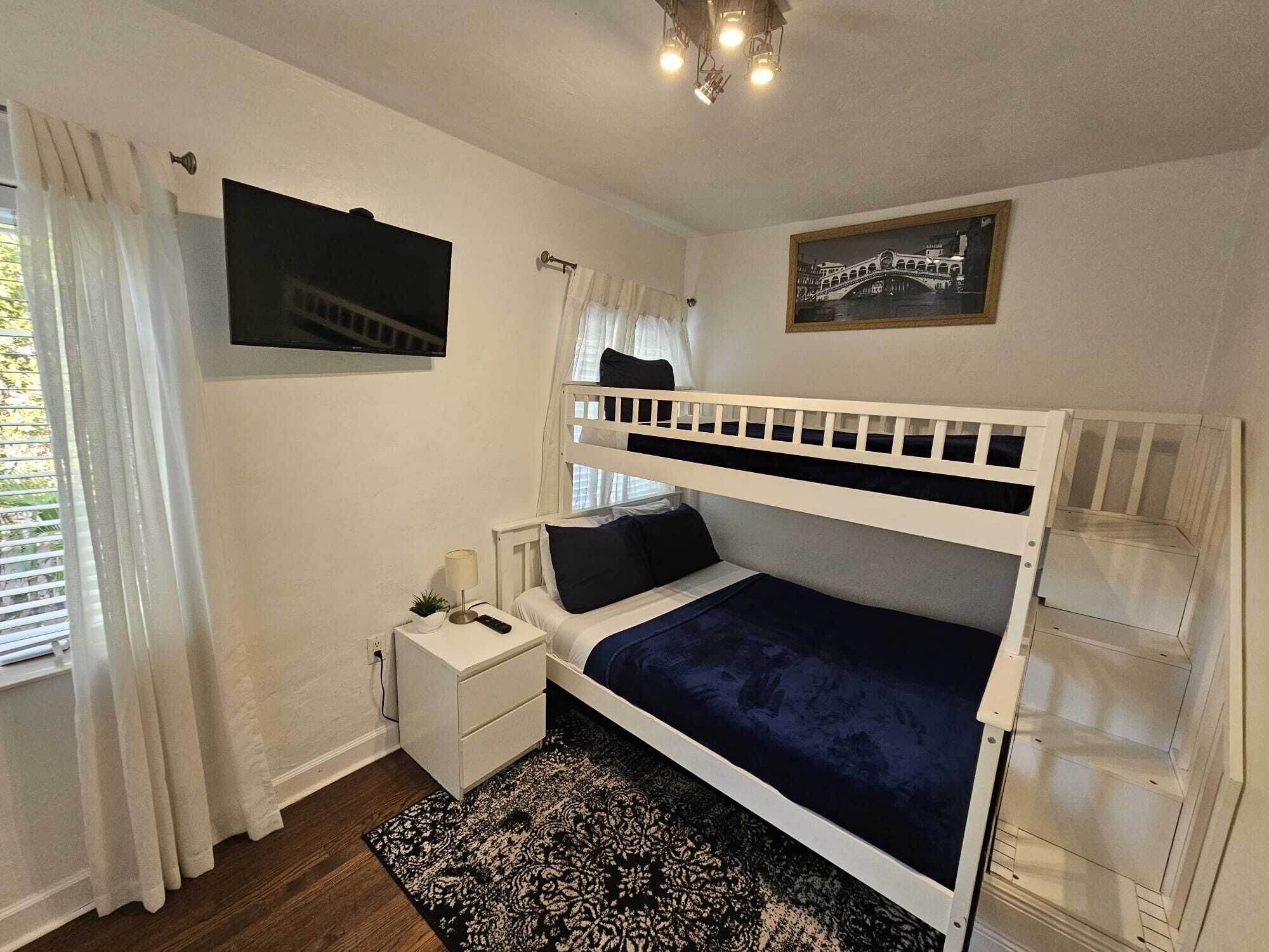 A bunk bed room with a TV, bedside table, and a framed picture on the wall.