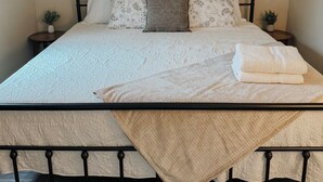 A neatly made bed with a quilt, pillows, and a blanket, a small bedside table with a plant, and a framed picture on the wall. - Charming 3BR / Close to Downtown / Pet Friendly (Panama City)