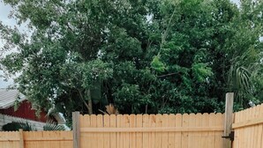 A backyard with a wooden table and grill, surrounded by a wooden fence and greenery. - Charming 3BR / Close to Downtown / Pet Friendly (Panama City)