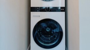 A compact, two-door washer and dryer unit in a narrow hallway with a light fixture above. - Charming 3BR / Close to Downtown / Pet Friendly (Panama City)