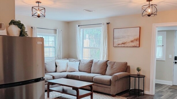 A modern living room with a sofa, coffee table, and a refrigerator. - Charming 3BR / Close to Downtown / Pet Friendly (Panama City)