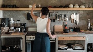 Cozinha com fogão, forno e diversos utensílios de cozinha pendurados na parede.