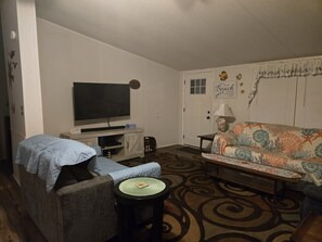 Ein Wohnzimmer mit Fernseher, Sofa und Sesseln.