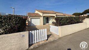 Un immobile residenziale con garage, recinzione bianca a paletti e cielo sereno.