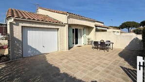 Una casa con garage, patio e area salotto all'aperto.