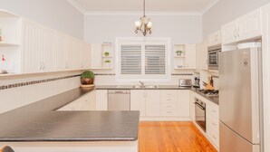 Een moderne keuken met witte kastjes, een centraal eiland, een vaatwasser, een fornuis en een koelkast.