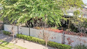 Een woonwijk met een witte picket fence, een verharde oprit en een huis met zichtbaar raam en deur.
